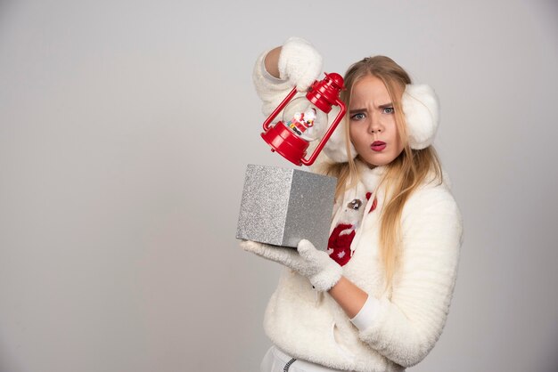 Mujer rubia en suéter blanco mostrando su regalo.