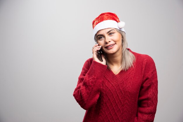 Mujer rubia en suéter rojo hablando por teléfono celular felizmente.