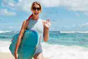 Foto gratuita mujer rubia con tabla de surf en la playa