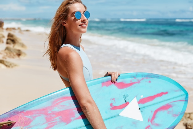 Mujer rubia con tabla de surf en la playa