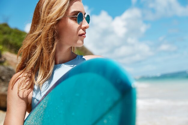 Mujer rubia con tabla de surf en la playa
