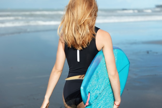 Mujer rubia con tabla de surf en la playa