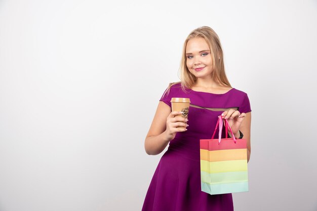 Mujer rubia con taza de café y bolso posando. Foto de alta calidad