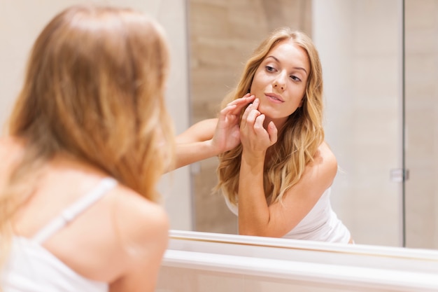 Foto gratuita mujer rubia tiene problemas con la piel de la cara.