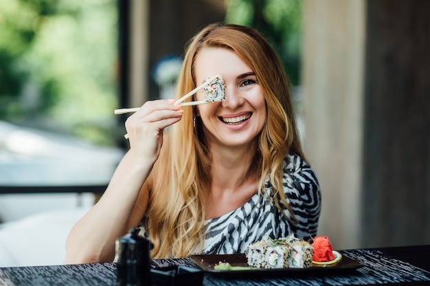 Mujer rubia tiene un tiempo de sushi en el restaurante