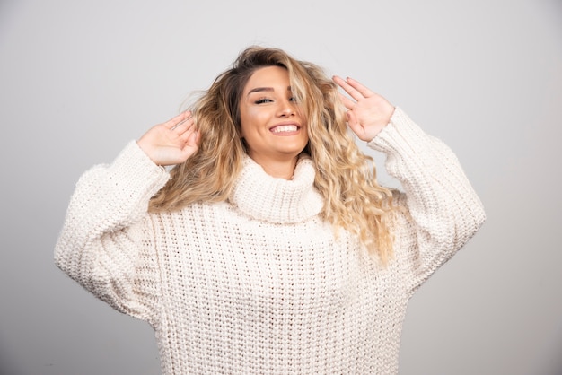 Mujer rubia en traje de invierno jugando con su cabello.