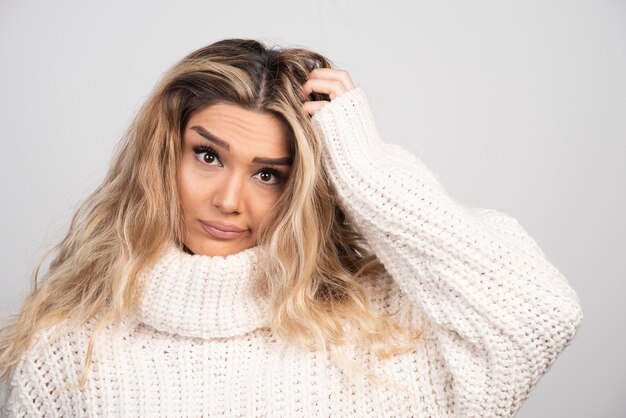 Mujer rubia en traje de invierno rascándose el pelo.