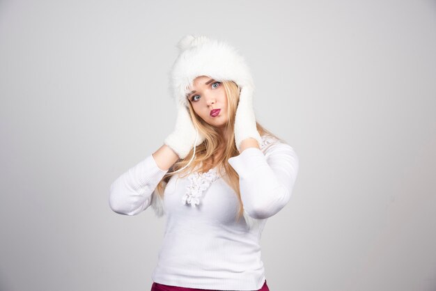 Mujer rubia en traje de invierno sosteniendo su rostro.