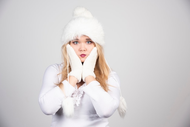 Mujer rubia en traje de invierno sosteniendo su rostro.