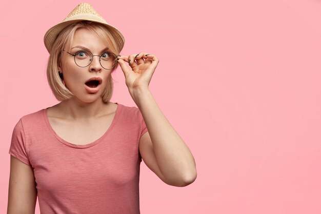 Mujer rubia vestida con camiseta rosa y sombrero