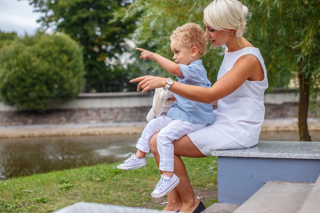 Una mujer rubia con vestido blanco y su pequeño y lindo hijo.