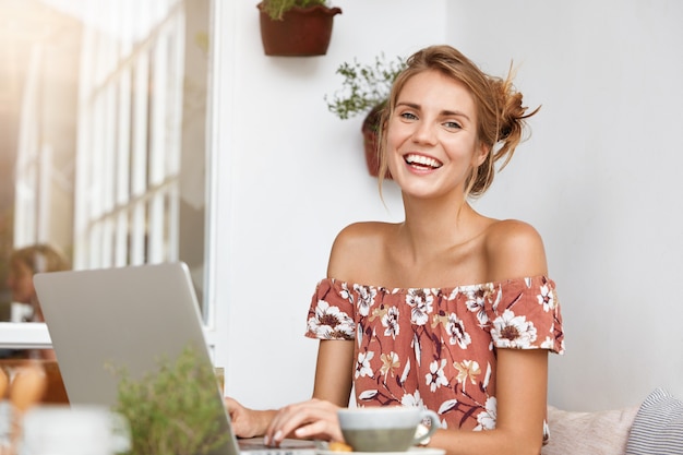 Foto gratuita mujer rubia en vestido floral en café