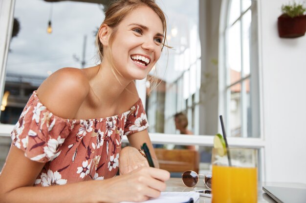 Mujer rubia en vestido floral en café