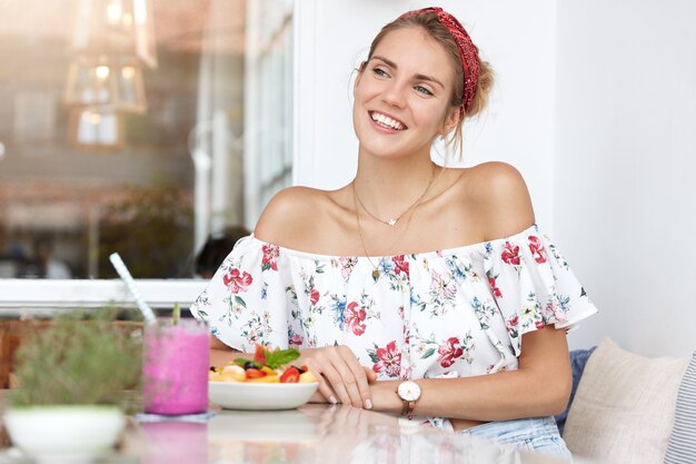 Mujer rubia en vestido floral en café