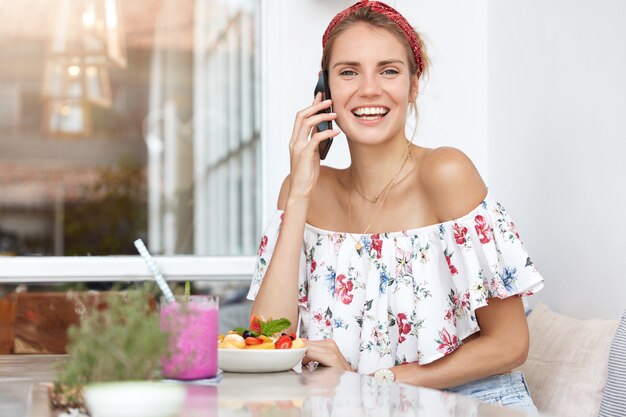 Mujer rubia en vestido floral en café