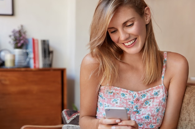 Mujer rubia en vestido floral sentado en el sofá