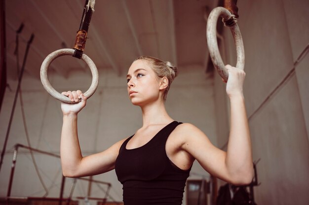 Mujer rubia vista frontal formación en anillos de gimnasia
