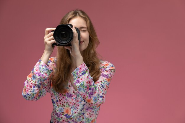 Mujer rubia de vista frontal tomando una foto de la persona que se para frente a ella