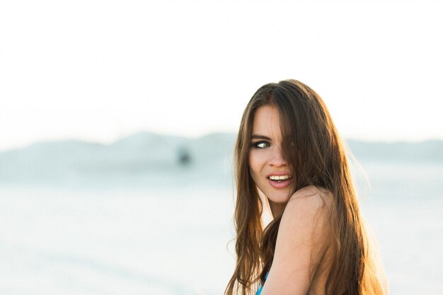 Mujer sacude su pelo posando en la playa