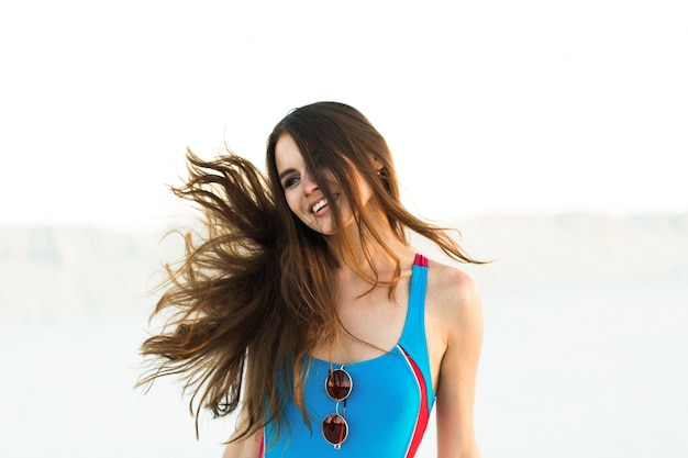 Mujer sacude su pelo posando en la playa