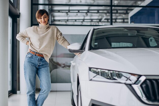 Mujer en una sala de exposición de automóviles eligiendo un automóvil nuevo