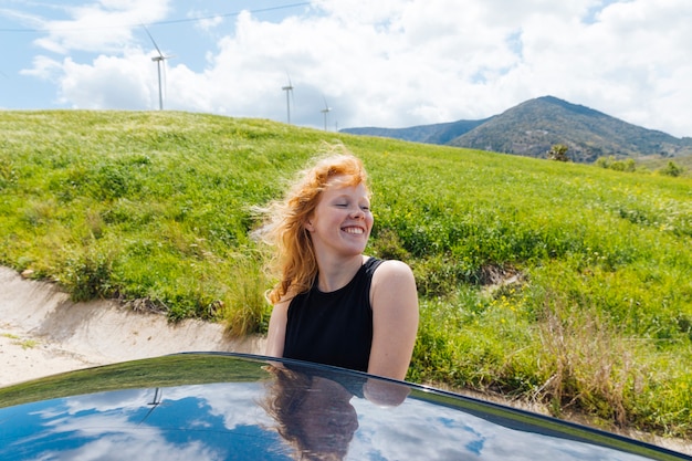 Mujer saliendo de la ventana del coche y poniendo cara al viento