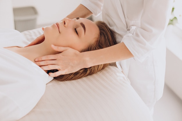 Mujer en un salón de belleza con masaje facial y de cuello