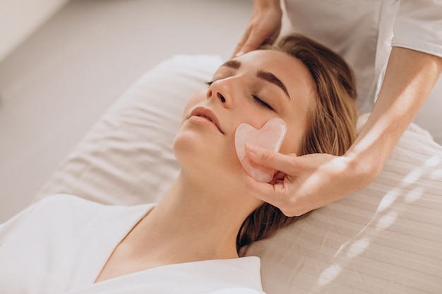 Mujer en el salón haciendo tratamientos de belleza con piedra gua sha