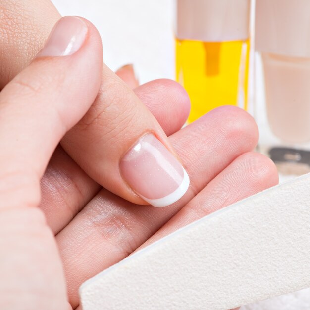 Mujer en un salón de uñas recibiendo manicura. Esteticista aplicando esmalte de uñas en una miniatura.