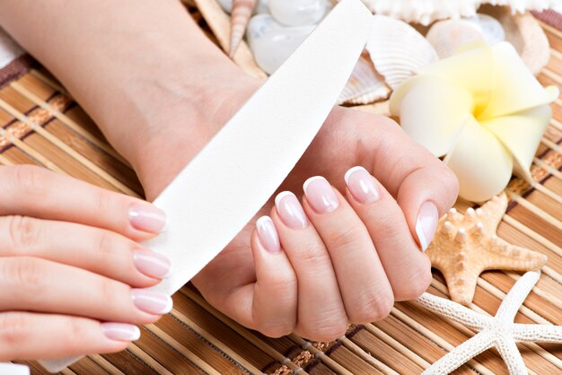 Mujer en un salón de uñas recibiendo manicura por una esteticista. Concepto de tratamiento de belleza.