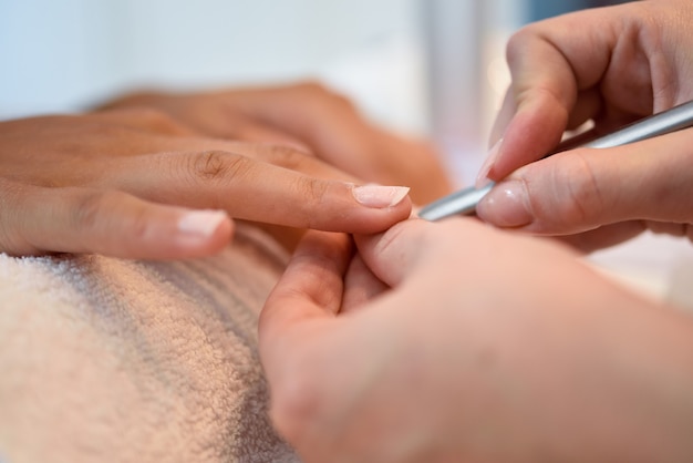 Mujer en un salón de uñas recibiendo una manicura con una lima de uñas