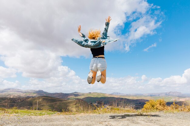 Mujer saltando de alegría en la cima de una colina