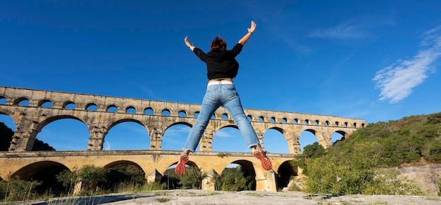 Foto gratuita mujer saltando delante de pont du gard francia