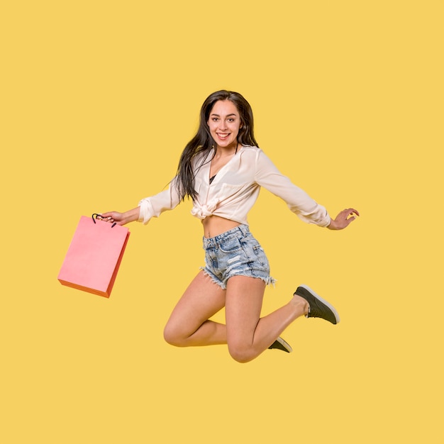 Foto gratuita mujer saltando feliz con bolsa