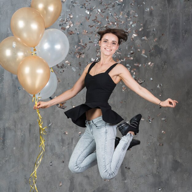 Mujer saltando con globos naranjas