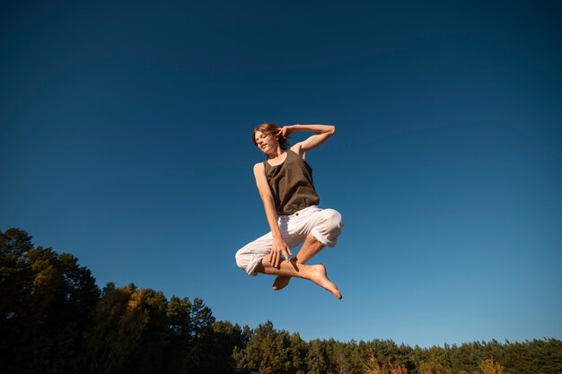 Mujer saltando en la naturaleza de ángulo bajo