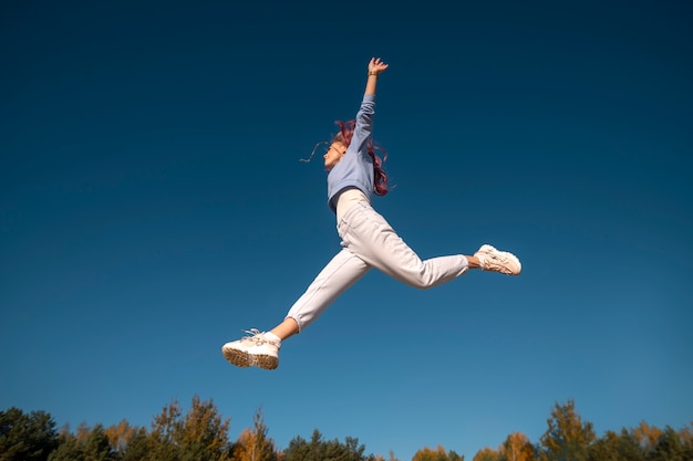 Mujer saltando en la naturaleza de ángulo bajo