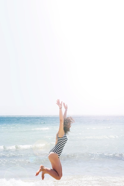 Mujer saltando en la playa