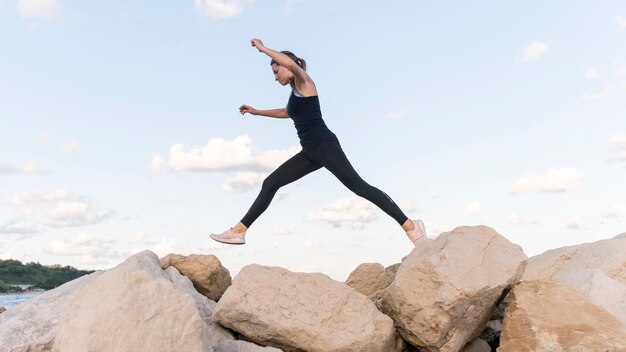 Mujer saltando sobre rocas