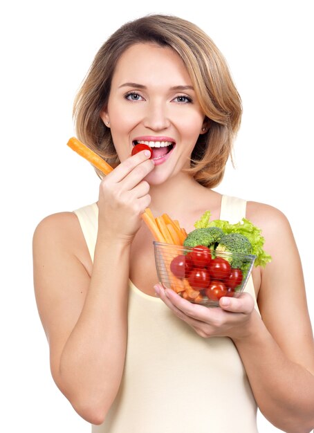 Mujer sana joven hermosa que come una ensalada aislada en blanco.