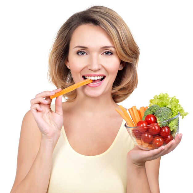 Mujer sana joven hermosa que come una ensalada - aislada en blanco.