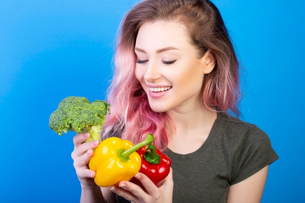Mujer sana mirando brócoli fresco pimiento rojo y amarillo