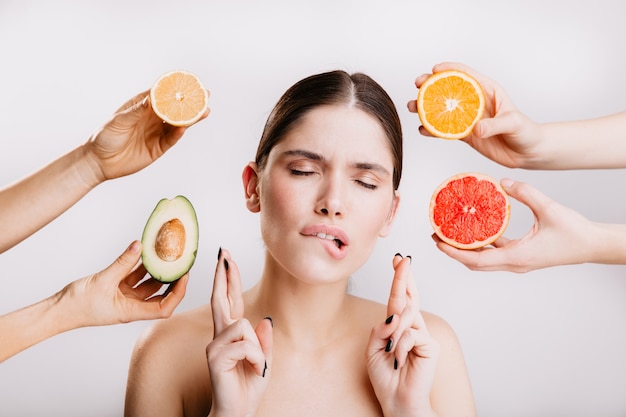 Mujer sana posando soñadoramente con los ojos cerrados, deseando deliciosas naranjas y aguacates.