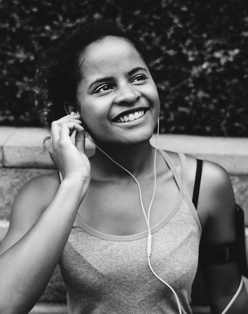 Mujer sana que ejercita mientras que usa tecnología