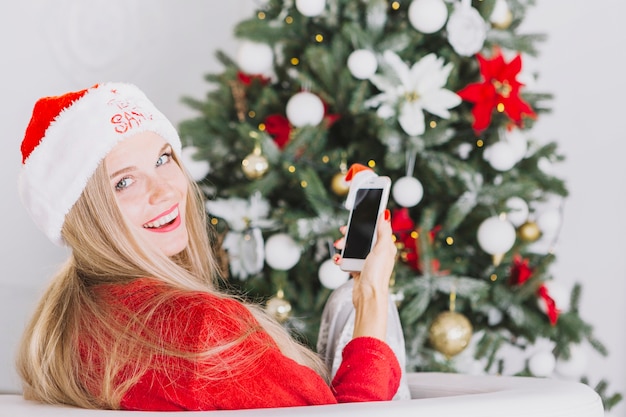 Foto gratuita mujer, en, santa sombrero, sentado, con, teléfono