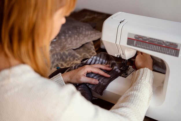 Mujer de sastre vista sobre el hombro con máquina de coser