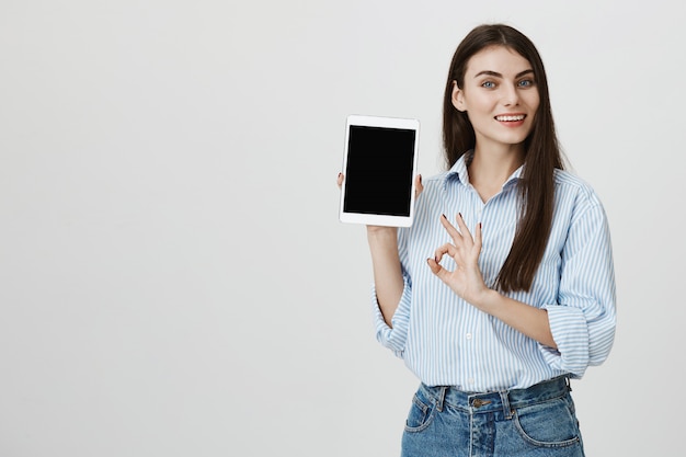 Mujer satisfecha mostrando tableta digital y signo bien