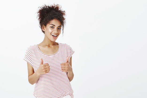 Mujer satisfecha con peinado afro posando en el estudio