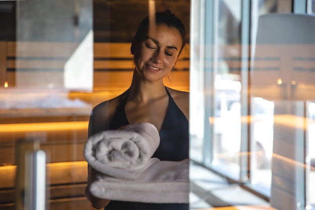 Una mujer en la sauna con toallas en las manos cerradas