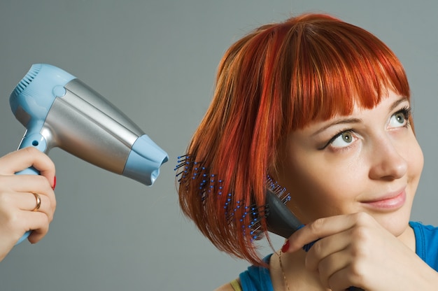 Foto gratuita mujer con secador de pelo y un cepillo para el cabello